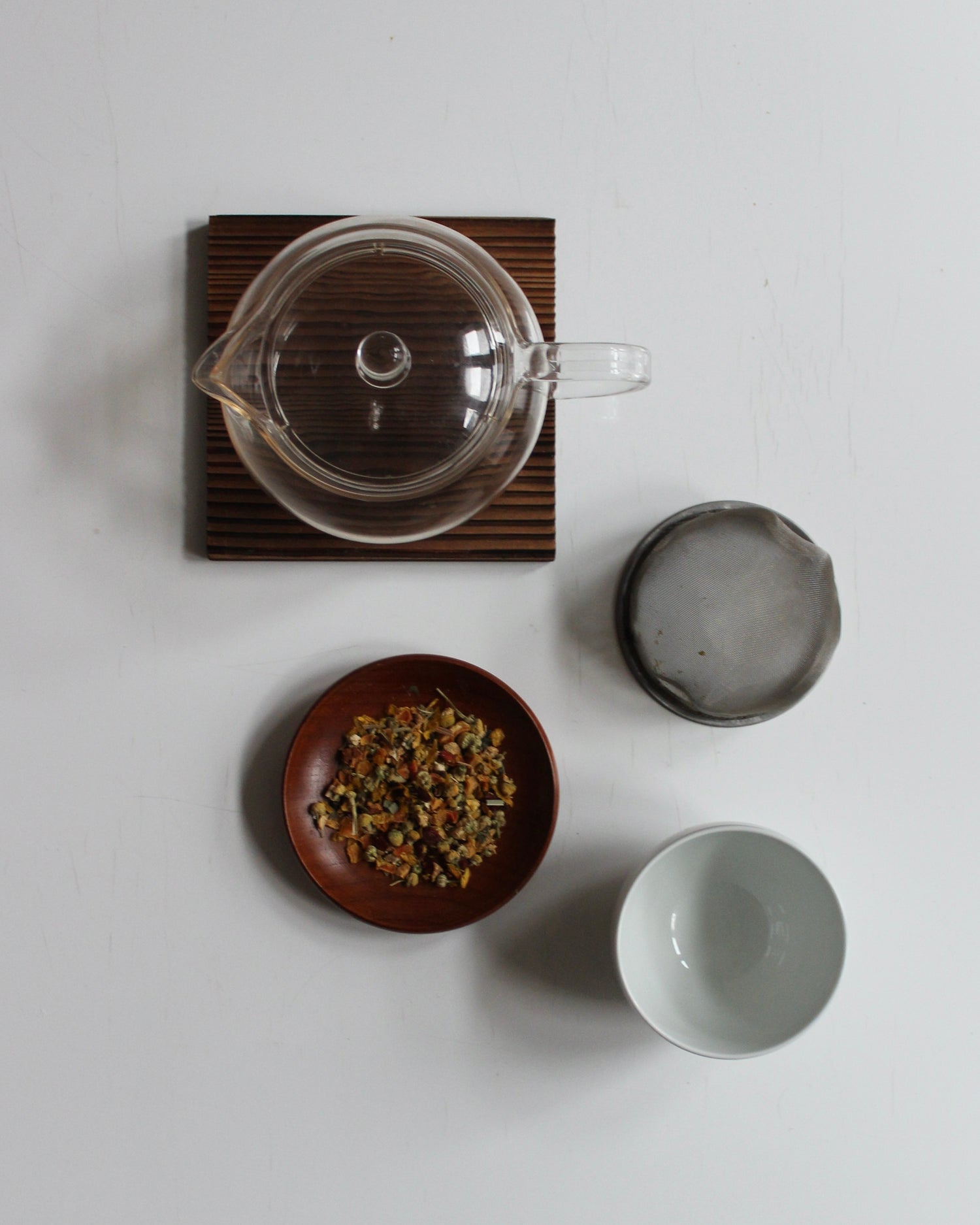 Tekande, tefilter, tekop og urteteblanding på bord